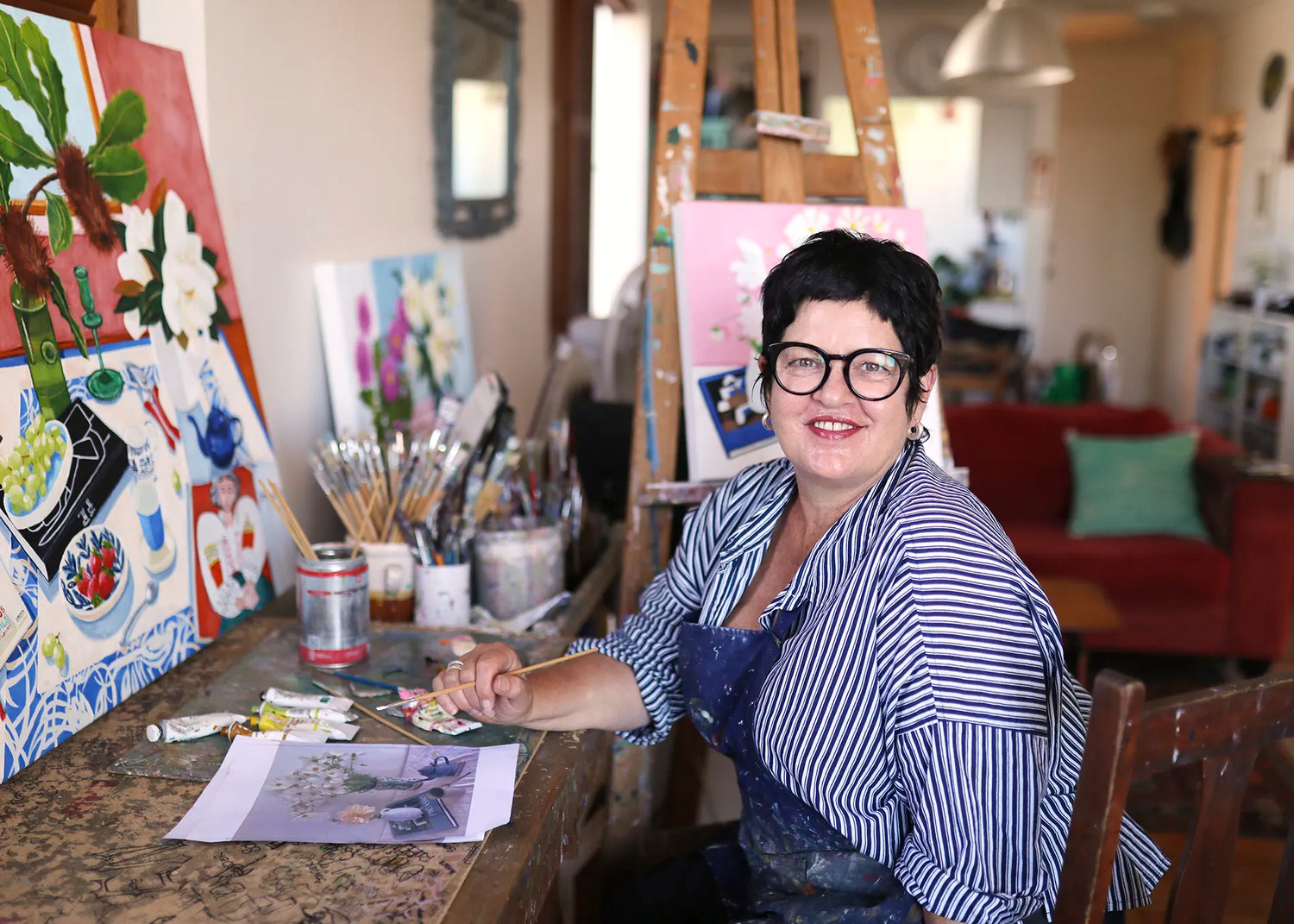 Melanie Vugich in her studio with paintings and art supplies around her